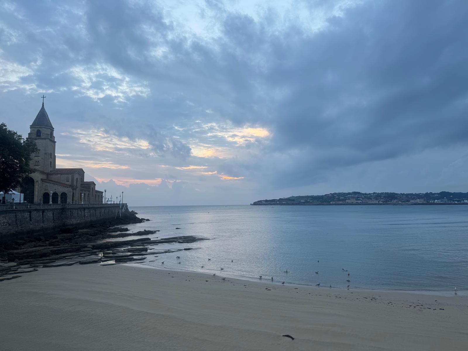 Playa de San Lorenzo vacía bajo un cielo cubierto al amanecer